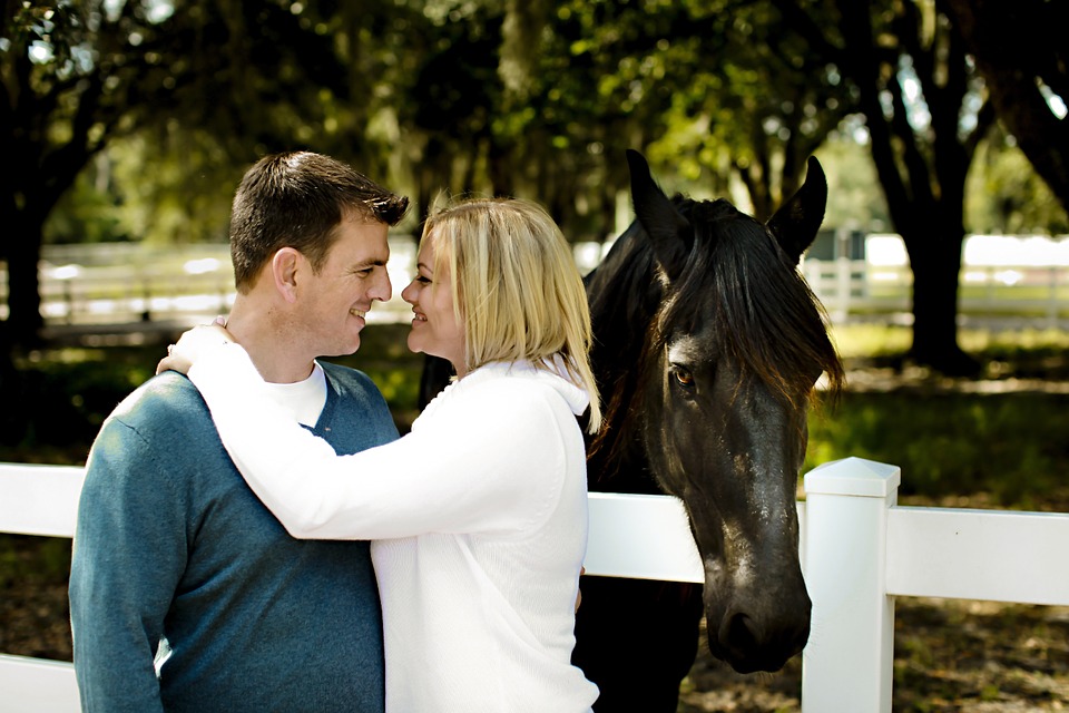 Couple gazing at each other near horse, tending their relationship.